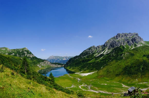 istock gorgeous green mountain landscape with a deep blue lake panorama 1299088476