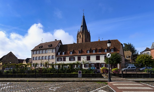Wissembourg, France, October 13, 2020: View of the Alsatian town of Wissembourg with the Catholic Church of Saints-Pierre et Paul on a sunny autumn day. It is situated on the little River Lauter close to the border between France and Germany.