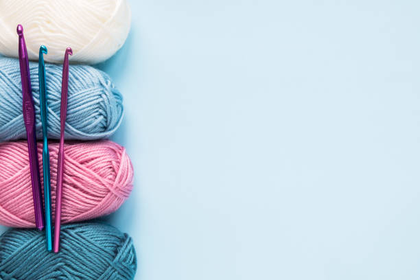 istock Multicolored crochet hooks with balls of yarn on a blue background with copy space. 1299089753
