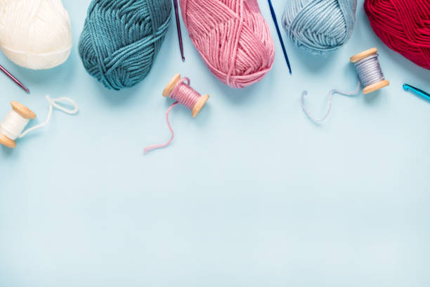 istock Multicolored crochet hooks with balls of yarn on a blue background with copy space. 1299089754