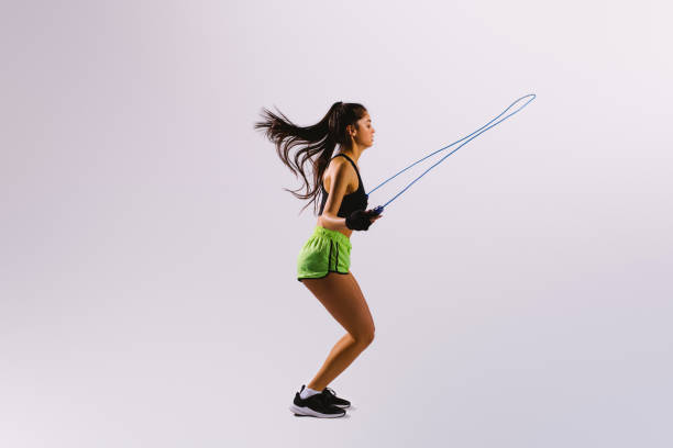 istock Sporty girl with jumping rope on white background with large empty side advertising space. 1299090735