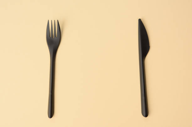 istock disposable black plastic fork and knife on a brown background, close up, set 1299091332