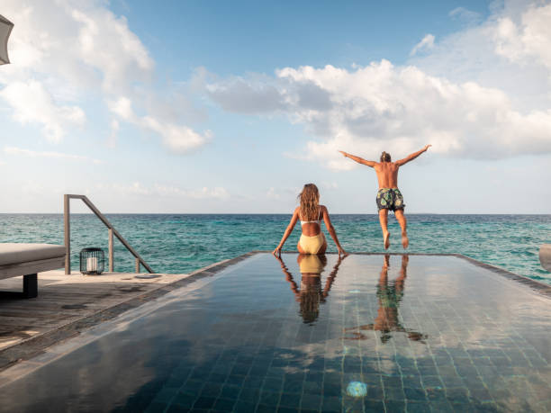 istock Couple enjoying luxury vacations, man jumping from pool to sea 1299092008