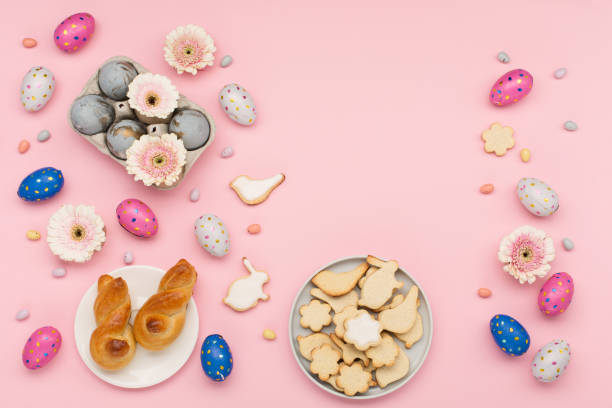 istock Homemade Easter bunny buns, sugar cookies, chocolate eggs, flowers on pastel pink background. Festive Easter breakfast concept. 1299092323