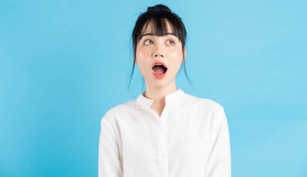 Woman, backgroung Beautiful Asian woman opening her mouth wide on blue background mouth open stock pictures, royalty-free photos & images