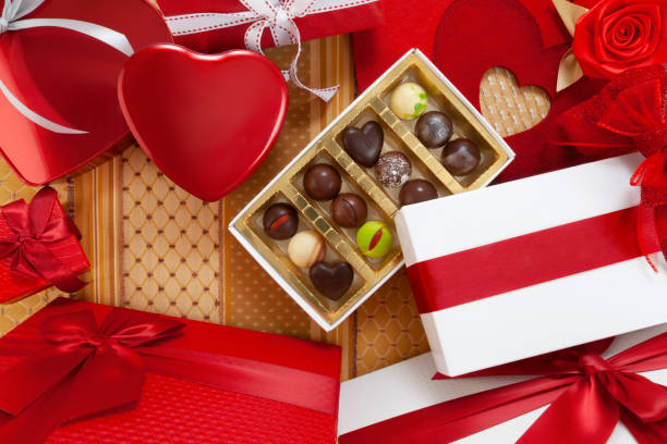 istock Valentines day background, composition of gift boxes chocolates and red heart metal shaped boxes, with bows and ribbons, top view on ornamental fabric. For greeting card or pastry poster template 1299094252