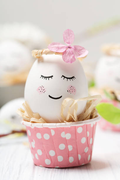 istock Easter holiday concept with cute handmade white eggs, tree branches, quail feathers and spring flowers on white wooden background. 1299095472