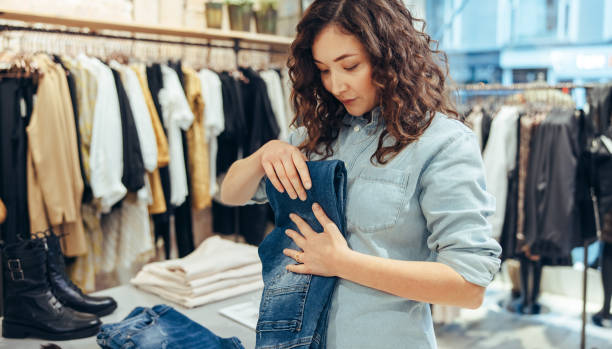 vendedora trabajando en tienda de moda - plegar fotografías e imágenes de stock