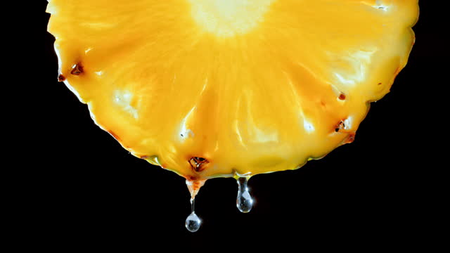 SLO MO LD Waterdrops falling off a pineapple slice