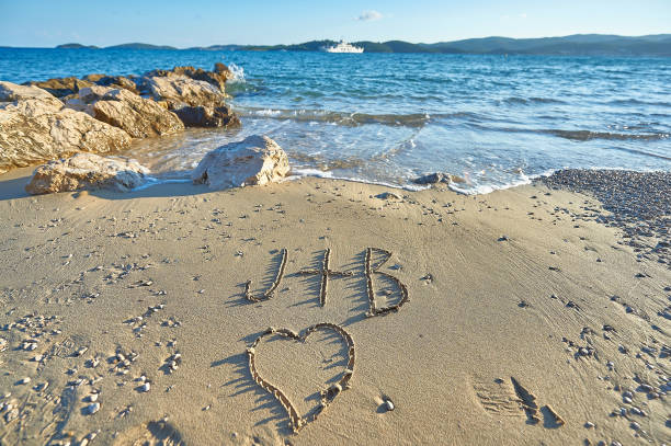 j plus b avec le coeur écrit sur la plage de sable fin - j key photos et images de collection