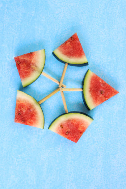 image of watermelon slices / chunks on popsicle sticks pentangle, cut into triangles, blue background, elevated view - pentangle imagens e fotografias de stock