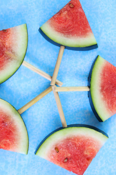 close-up image of watermelon slices / chunks on popsicle sticks pentangle, cut into triangles, blue background, elevated view - pentangle imagens e fotografias de stock