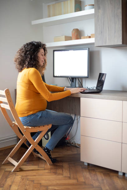 istock Pregnant woman using laptop at home 1299101685