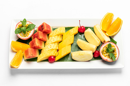 mixed fresh cut organic fruit salad platter on white background