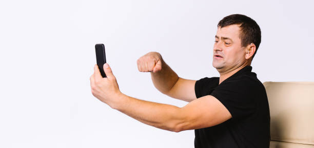 Banner,long format. Senior man communicates with the help of gestures via video communication showing yes gesture while sitting in a chair. White background with side space. High quality photo