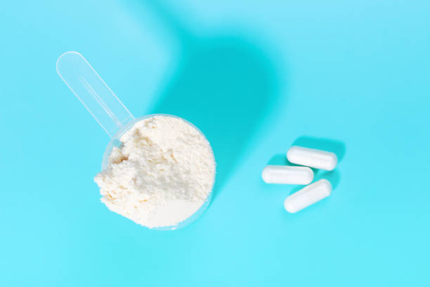 istock Scoop with protein powder and capsules on blue background top view. 1299105602
