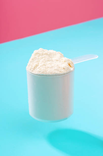 istock Protein powder in scoop on blue and pink background front view. 1299105737