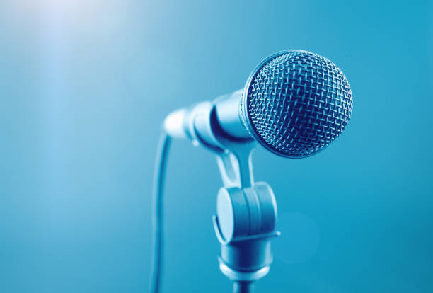 Vocal dynamic microphone under stage lights, ready for singer or public speaker Close-up of a microphone under bright lighting. microphone stand stock pictures, royalty-free photos & images