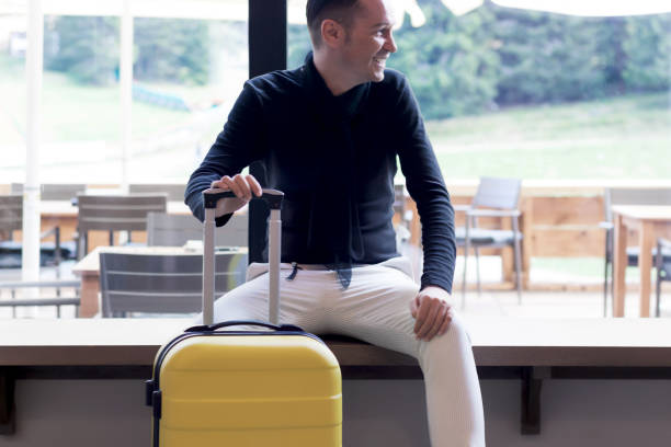 istock Happy mid adult man sitting with travel bag in a hallway. 1299106607
