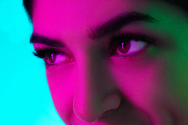 istock Close up beautiful woman's eyes isolated on blue studio background in multicolored neon light 1299107209