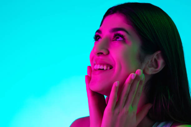 istock Brunette beautiful woman's portrait isolated on blue studio background in multicolored neon light 1299107211
