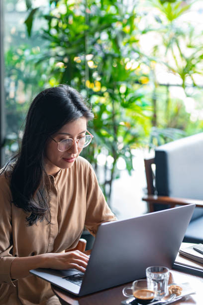 istock Asian Woman/College Student Using a Laptop Computer to Study Remotely at a Cafe 1299107316