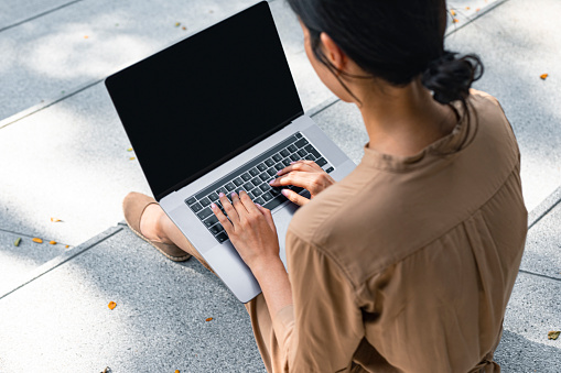 Woman using a laptop computer with a blank screen outdoors