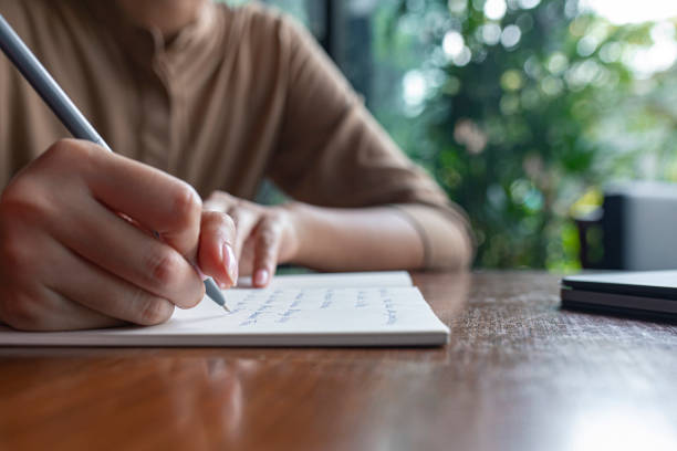 istock Hands of an Anonymous Woman Writing Notes in her Notebook, a Close Up 1299107396