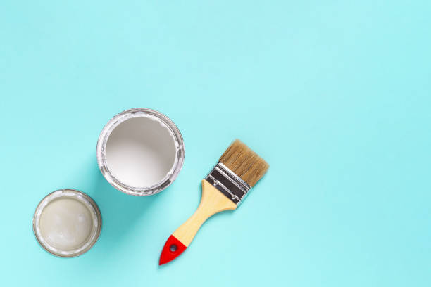 istock Paint brush with wooden handle and open white paint can on a cyan blue background. Construction painting work, repair and redecorate concepts. 1299108051