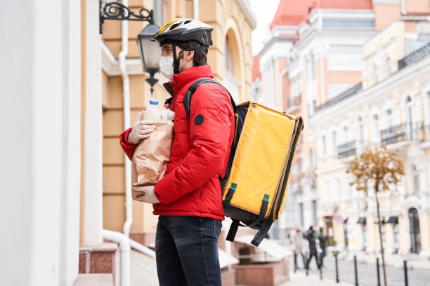 istock Courier wearing protective mask and gloves standing is under the door 1299108124