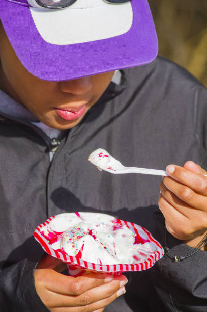 young girl tastes a very good and tasty ice cream with cream, berries jelly and candies