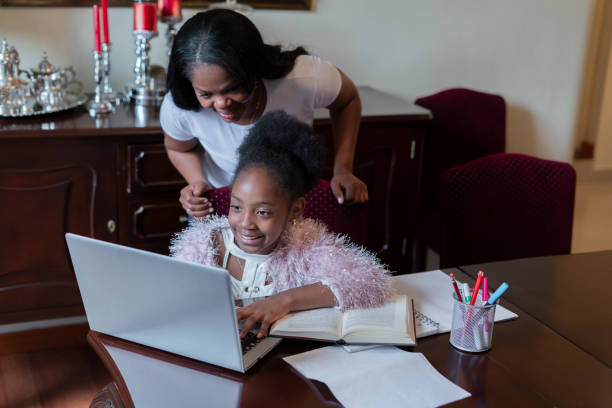 istock Afro mom and daughter do their homework from their dining room using their laptop to do homework 1299109621