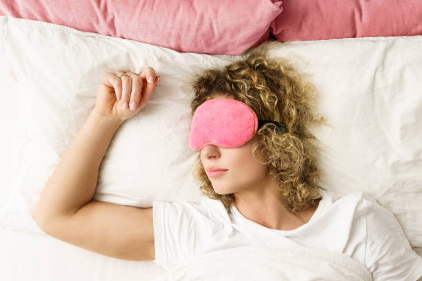 istock Beautiful woman sleeping with a pink blindfold on her eyes 1299111169