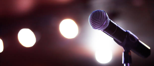 istock Microphone on abstract blurred of speech in seminar room or speaking conference hall light 1299113483