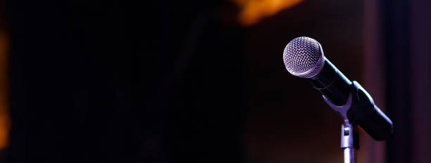istock Microphone on abstract blurred of speech in seminar room or speaking conference hall light 1299114076