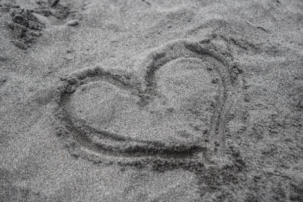 istock Drawing symbol of love on the sand 1299114811