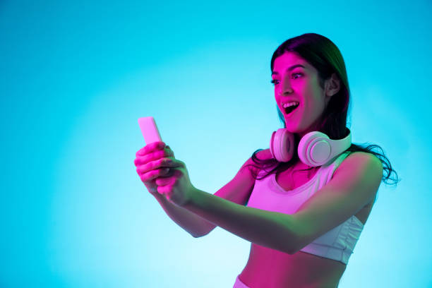 istock Brunette beautiful woman's portrait isolated on blue studio background in multicolored neon light 1299115064