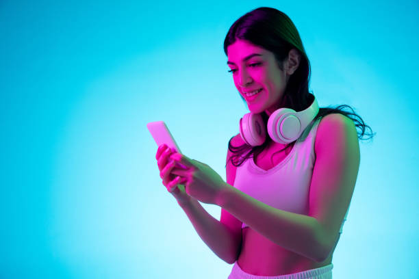 istock Brunette beautiful woman's portrait isolated on blue studio background in multicolored neon light 1299115075