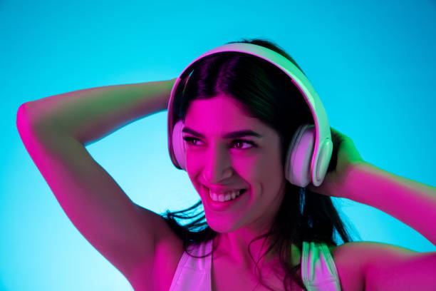 istock Brunette beautiful woman's portrait isolated on blue studio background in multicolored neon light 1299115078