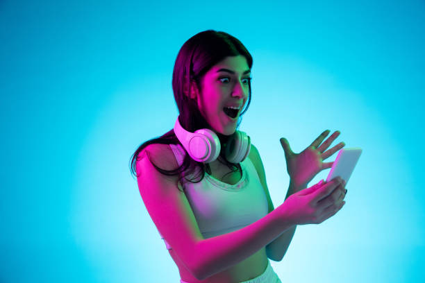 istock Brunette beautiful woman's portrait isolated on blue studio background in multicolored neon light 1299115083