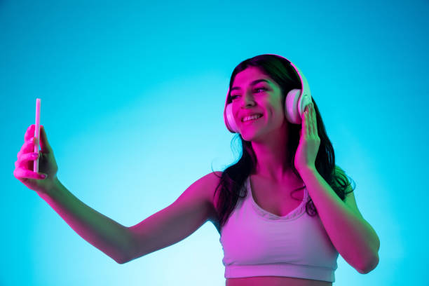 istock Brunette beautiful woman's portrait isolated on blue studio background in multicolored neon light 1299115084