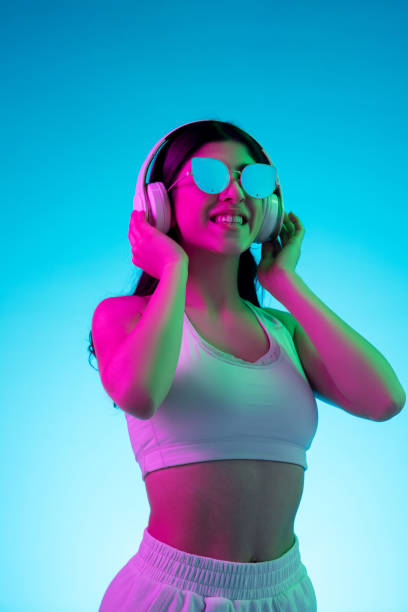 istock Brunette beautiful woman's portrait isolated on blue studio background in multicolored neon light 1299115097