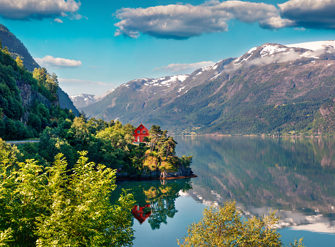 Impressive summer view of red painted house on the shore of Hardangerfjord fjord, Hordaland county, Norway. Beauty of countryside concept background.