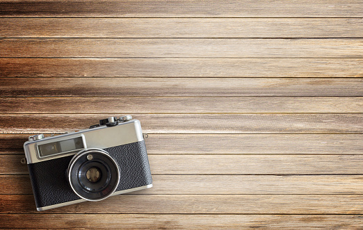 Retro camera on wood table background, vintage color tone. top view with copy space for use