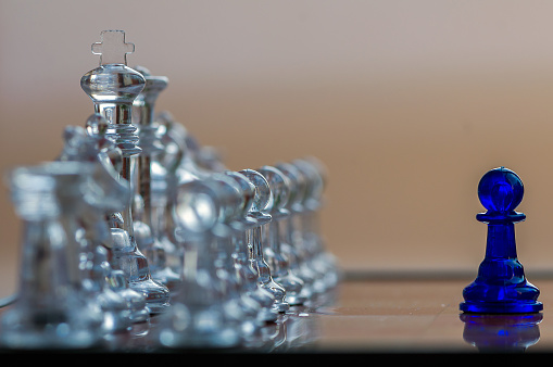 Close-up of a transparent king chess piece sitting on a chessboard. Shallow depth of field.