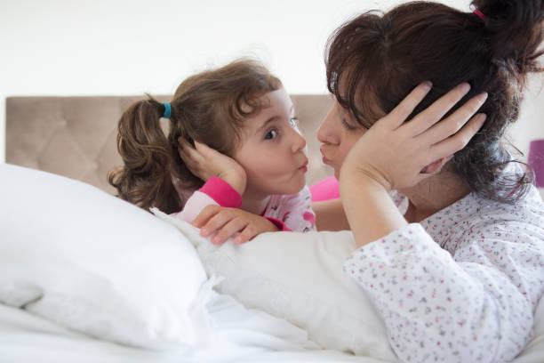 istock Mother and daughter kiss on their bed 1299122325