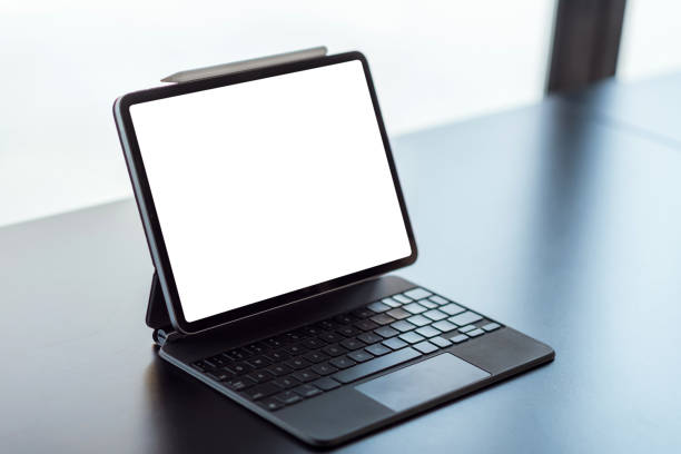 istock Mock up. blank screen digital tablet with office supplies on black wooden table. 1299122427