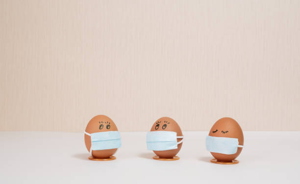 istock Easter eggs with virus protection concepts. Easter eggs in a medical mask to decorate the Easter holidays. On a peach background with copyspace. 1299122707