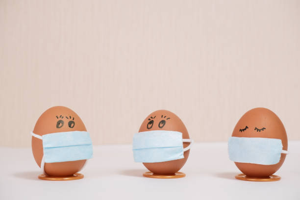 istock Easter eggs with virus protection concepts. Easter eggs in a medical mask to decorate the Easter holidays. On a peach background with copyspace. 1299122772