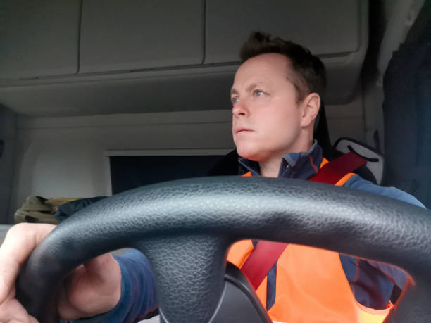 conducteur de camion utilisant un gilet de haut vis et la vue rouge de ceinture de sécurité de l’avant avec le conducteur regardant droit - semi truck truck red truck driver photos et images de collection